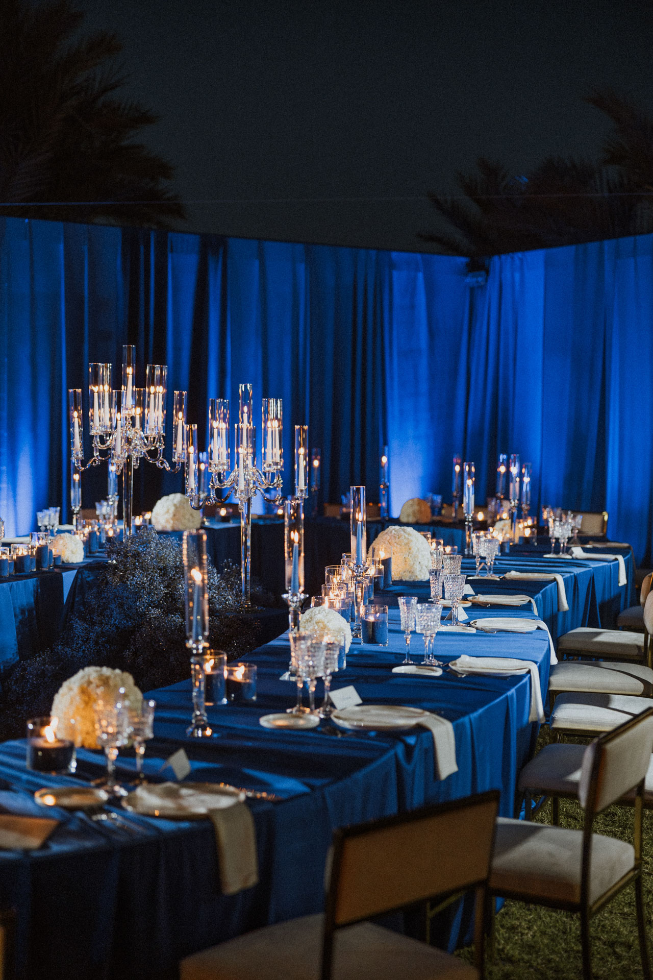 Boda nocturna en monocromía azul con velas, ejemplo de la tendencia azul en decoración de bodas contemporáneas